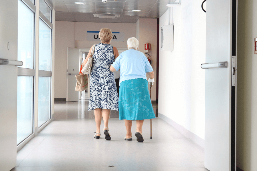 Elderly mom and daughter walking into an assisted living home making the transition from aging in place to assisted living
