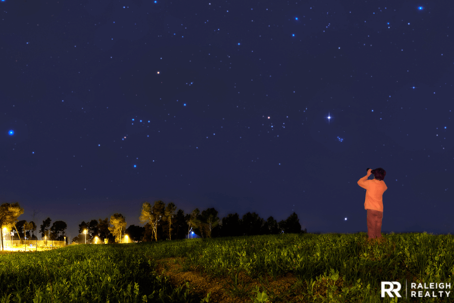 A kid gazing at stars in the backyard at night time with a telescope