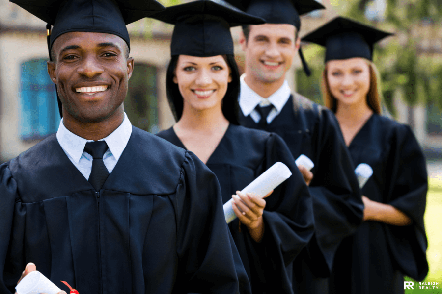 College graduates holding their diplomas standing in a line on graduation day with big smiles on their faces