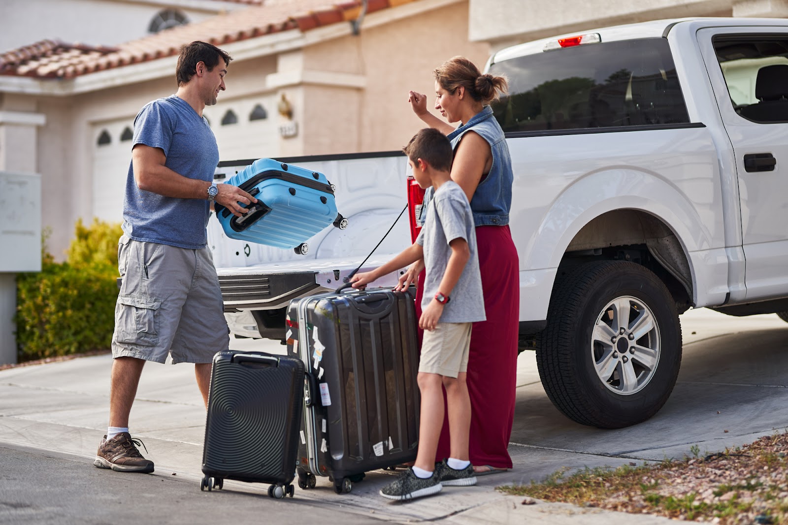 A family packing their luggage in the back of their truck to go on a trip.