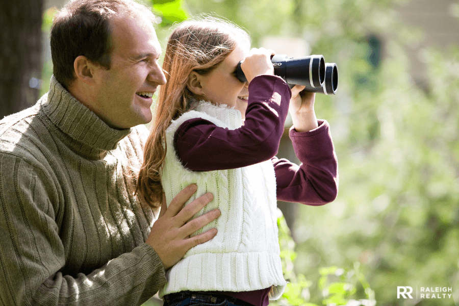 Girl and father watching birds in their backyard at home