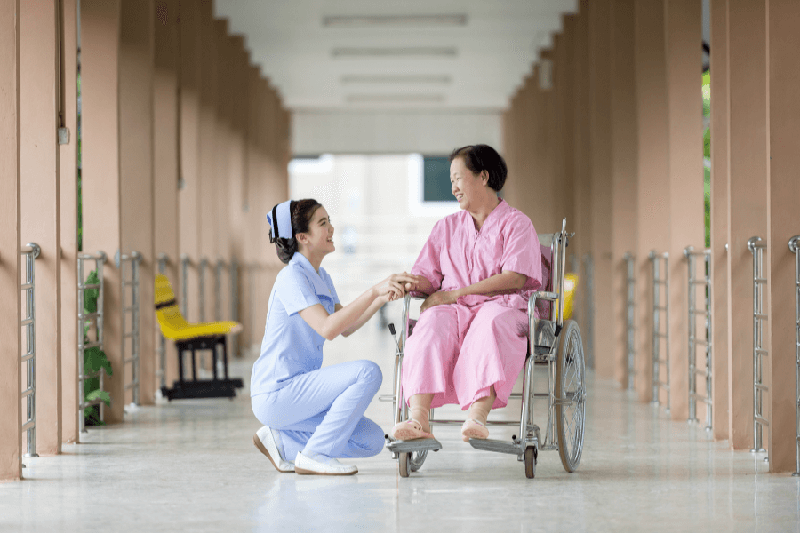 A senior woman in a wheelchair meets nurse in hallway of an assisted living center