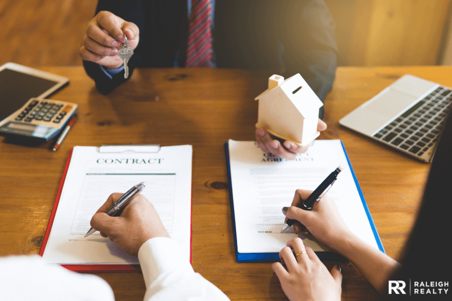 People signing a real estate contract and being handed the keys at the closing table