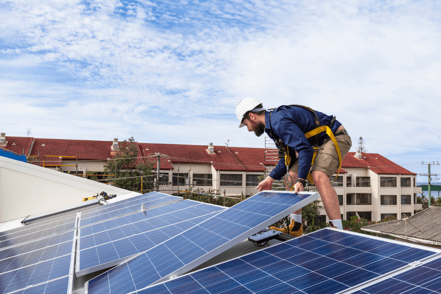 Worker installing solar panels on the roof of home.