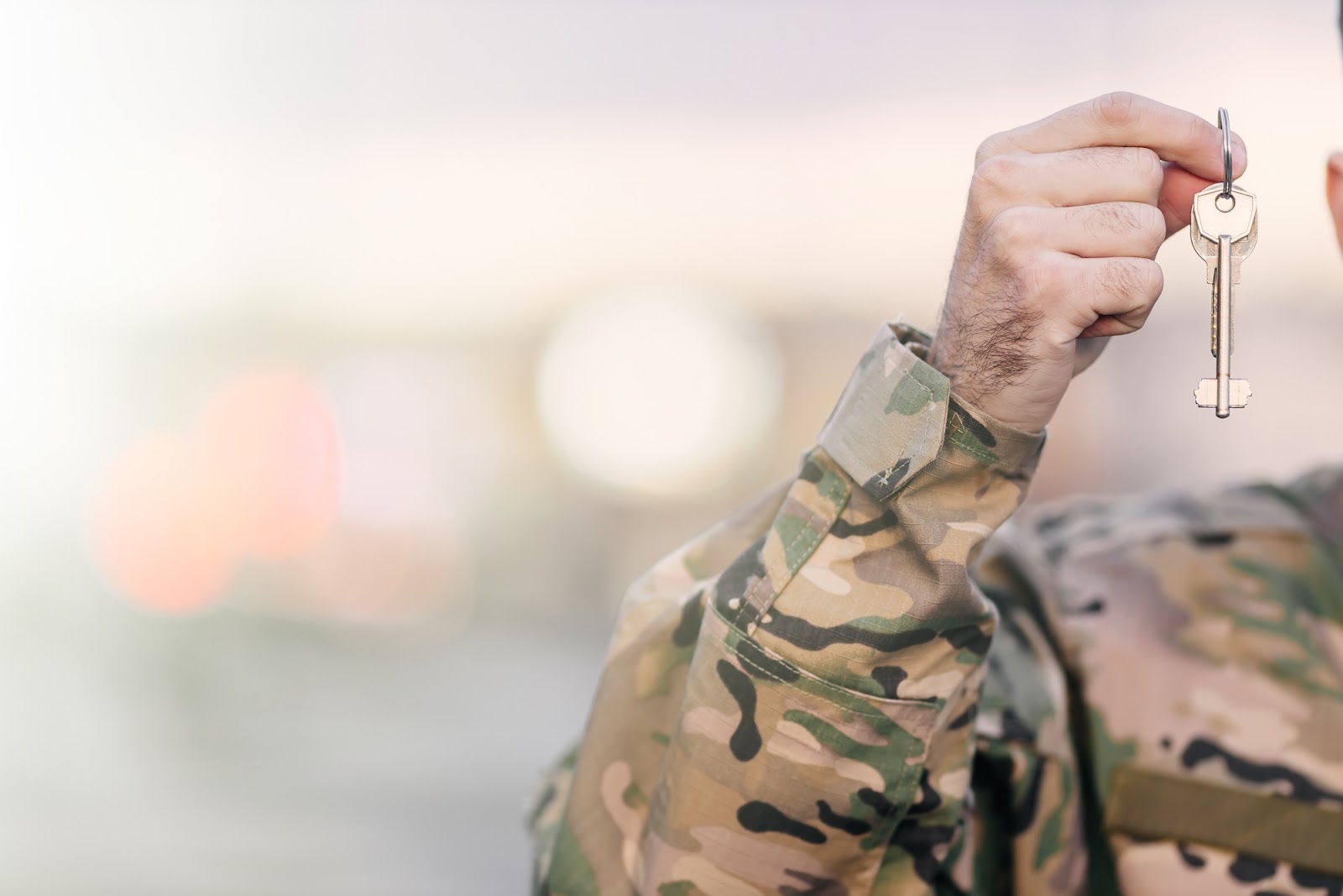 A closeup of a person in military garb holding the keys to a house.