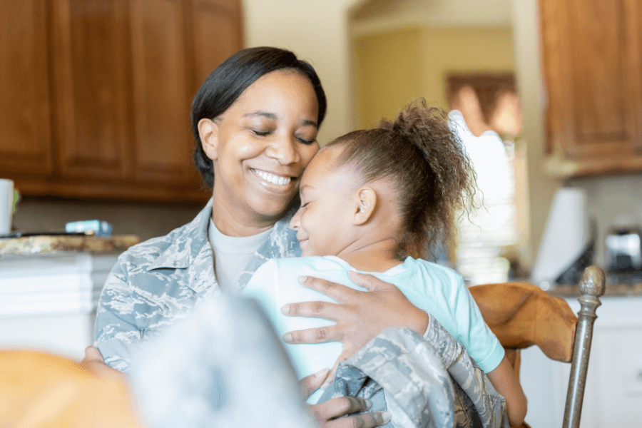 A mom in military uniform and daughter sitting together in kitchen
