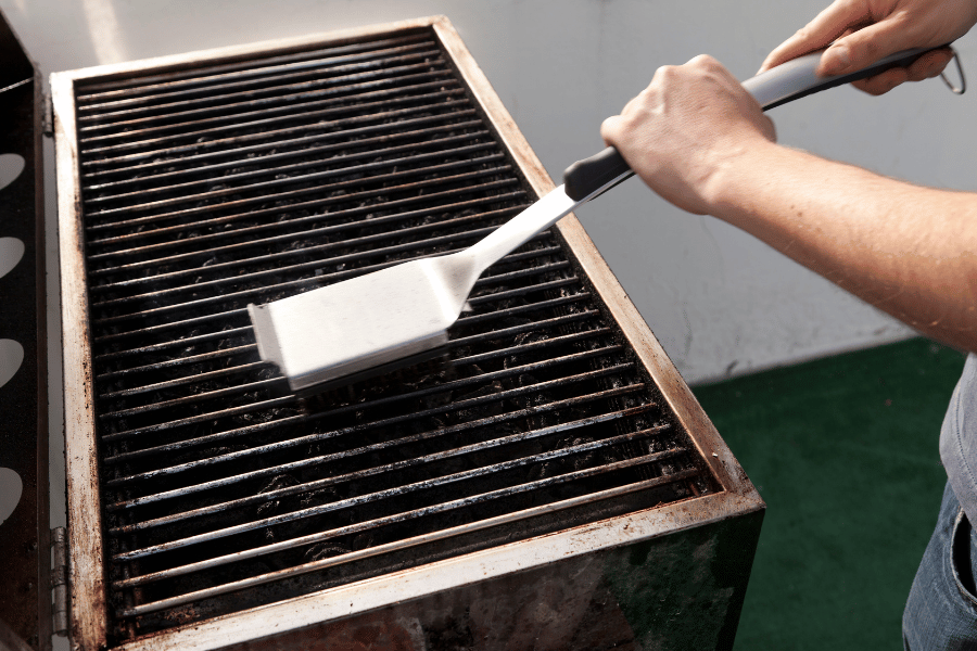 Man cleaning a grill outside after use 