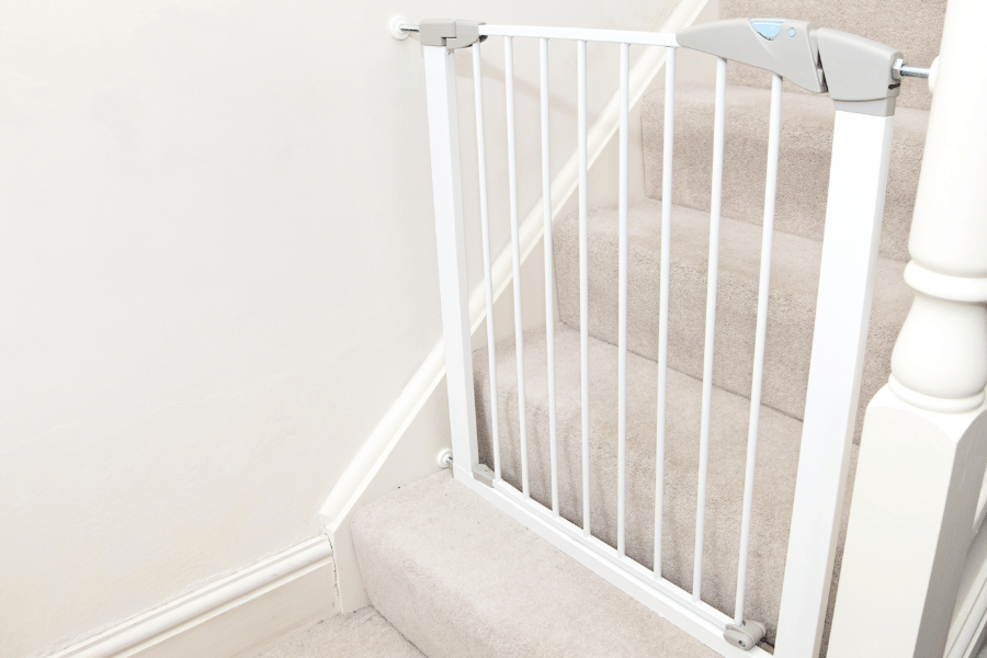 white baby gate on carpeted stairs to keep children safe