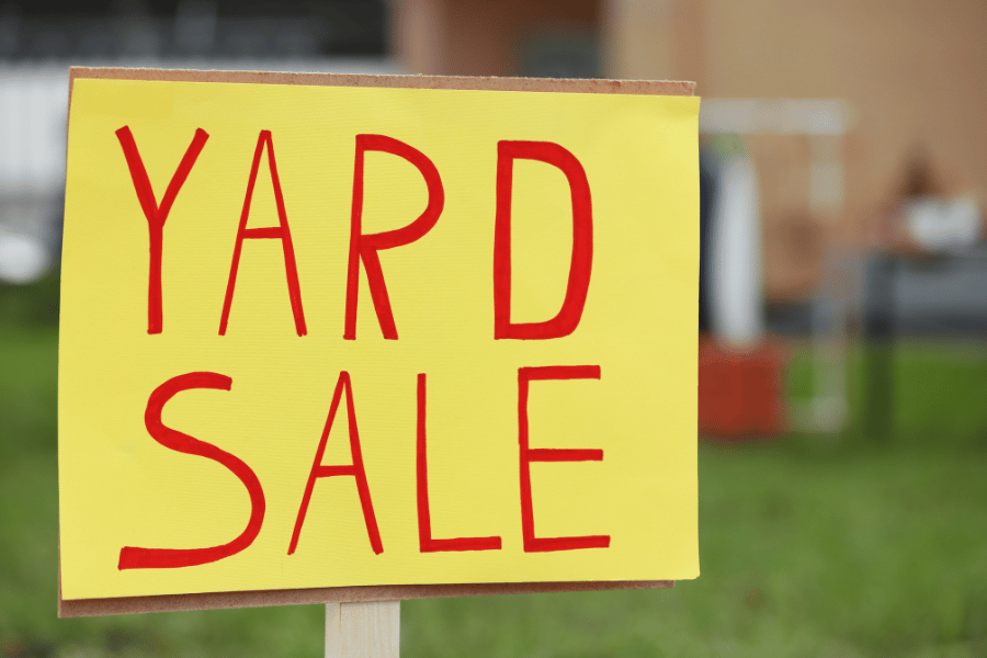 red and yellow yard sale sign in yard to sell unused items