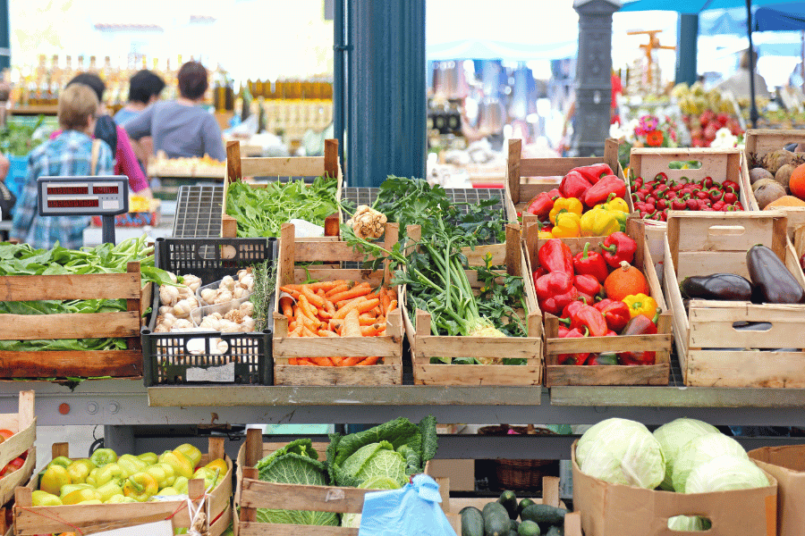 Fresh Produce Stands at Farmers Market With People Shopping