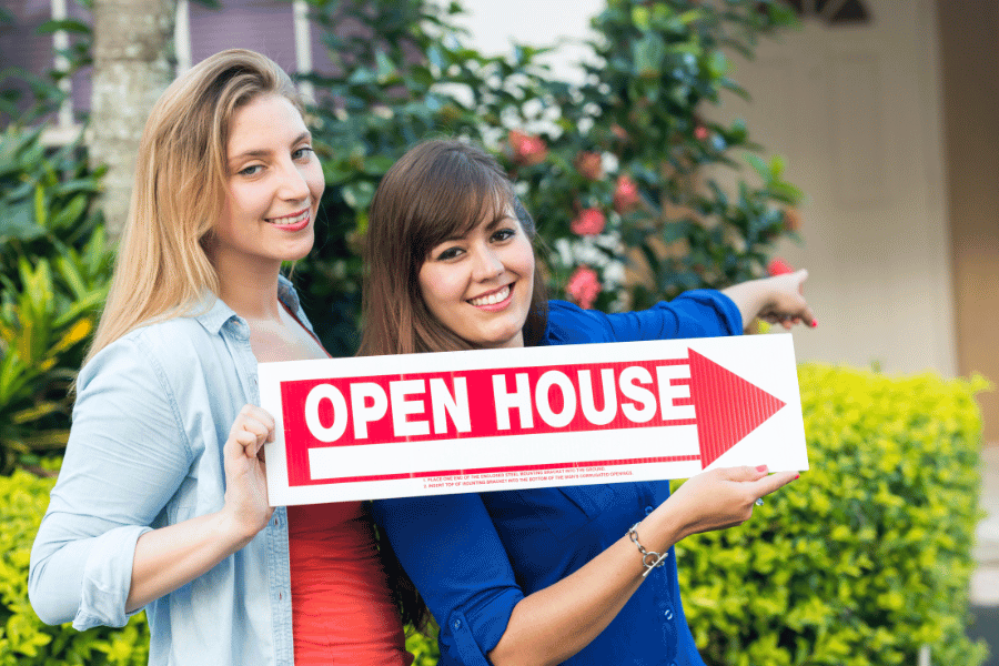 friends holding a red open house sign 