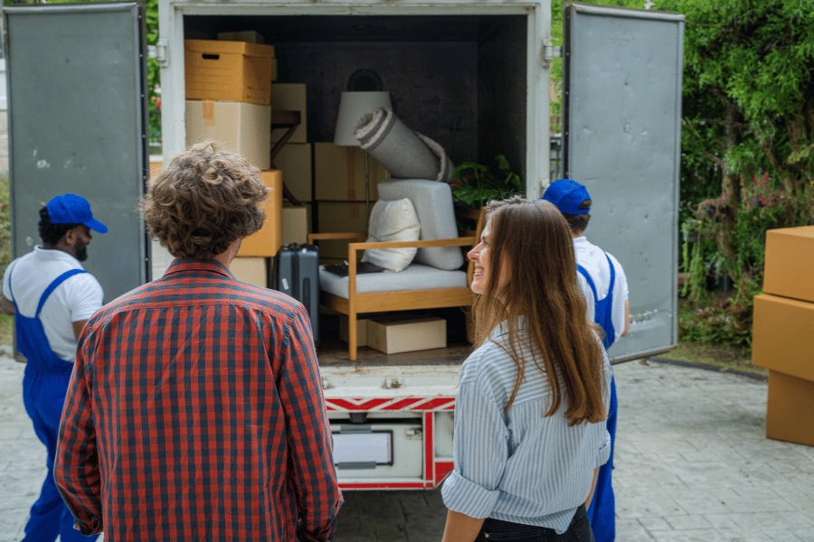 couple watching their belongings be loaded into the back of a moving truck
