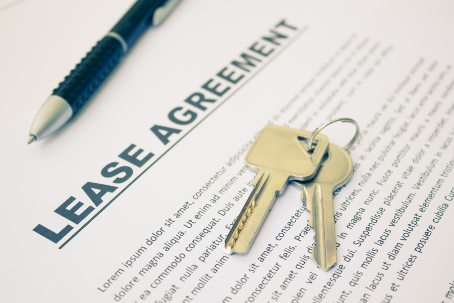 Lease agreement with pen and gold keys on white paper