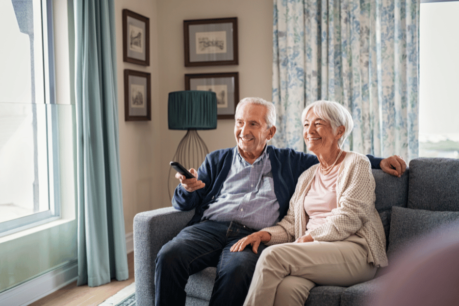 older couple at home watching tv together from their couch 