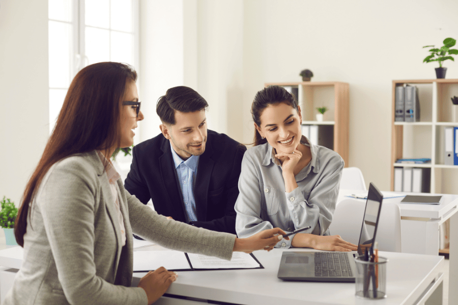 Clients meeting with a real estate agent and talking at their desk