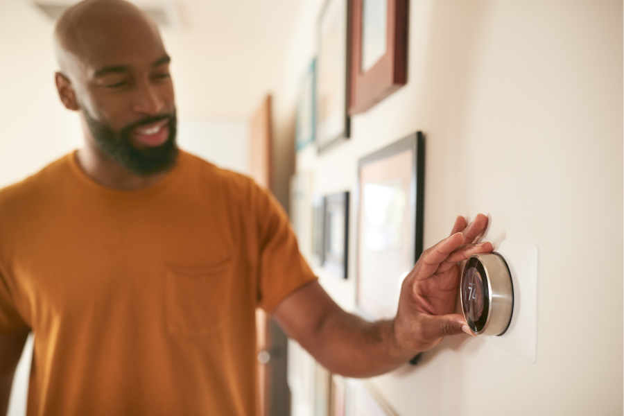 Photo of man in beige shirt adjusting thermostat