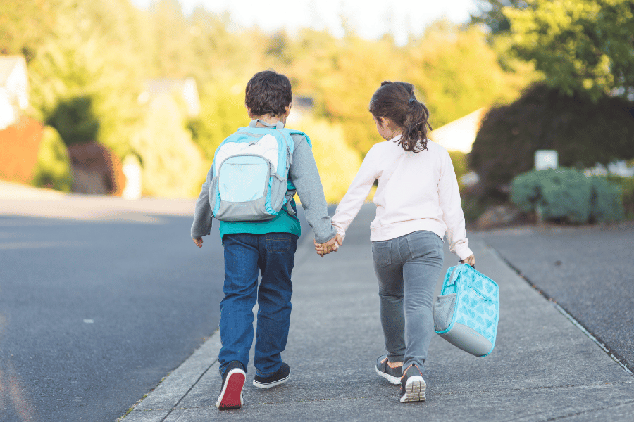 two young children walking to school and holding hands