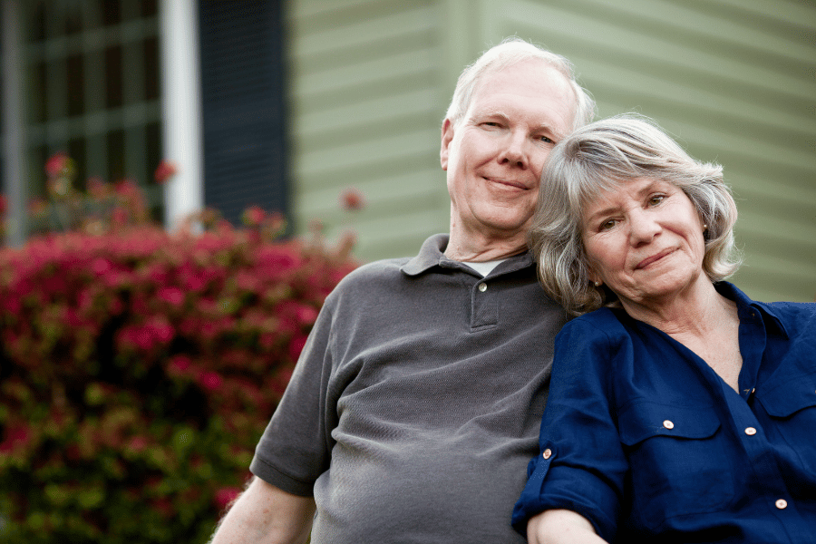 cute Baby Boomer couple happy to be together and sitting outside of their home 