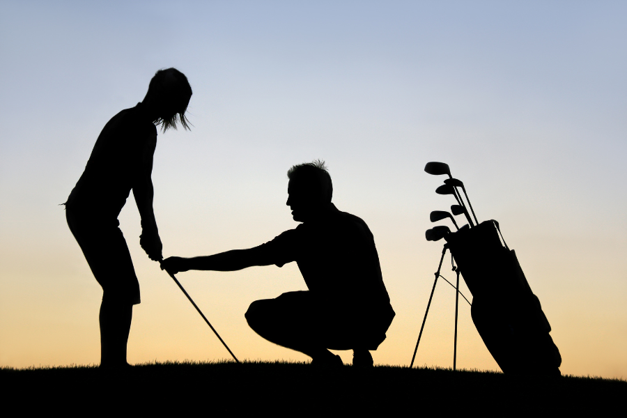 Silhouette of Woman Standing with golf club and man instructing