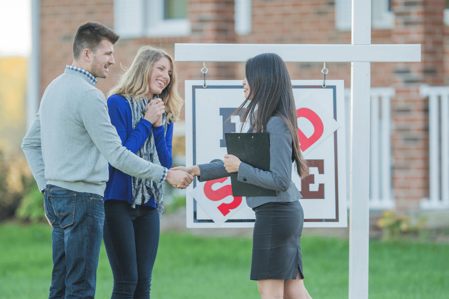 couple buying a home and shaking the hand of a real estate agent