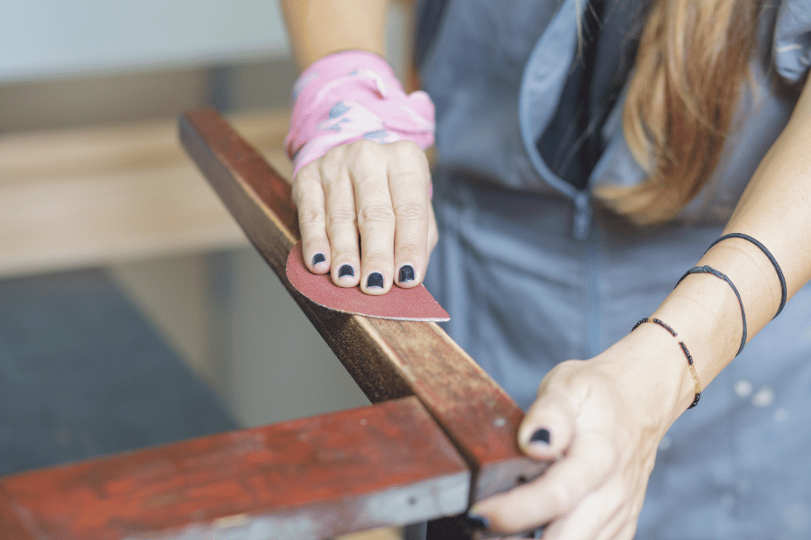 woman restoring furniture by sanding down wood