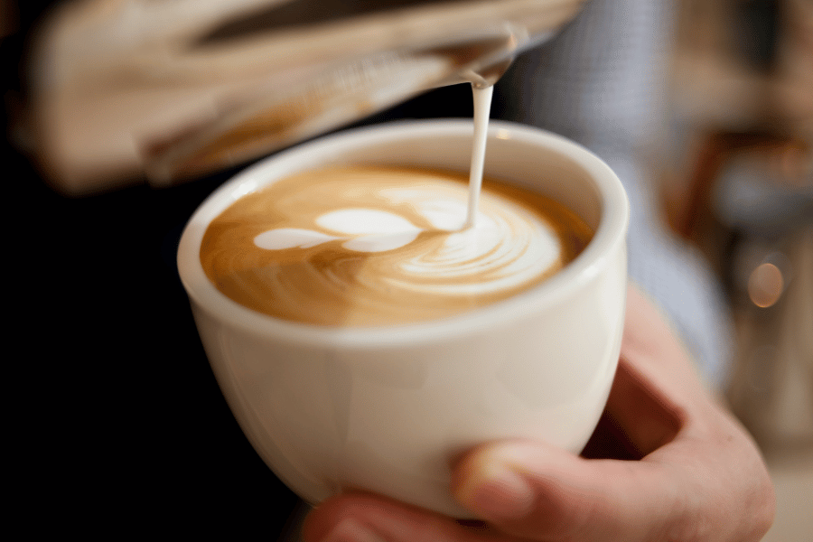 pouring coffee and latte art in a white mug