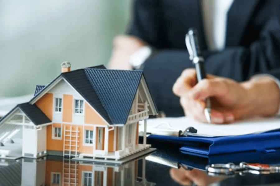 Model of home on a table and writing on paper 