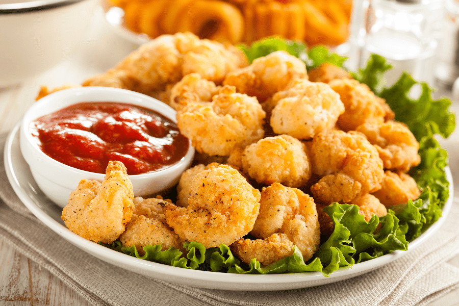 popcorn shrimp on a bed of lettuce with sauce