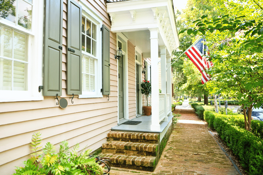 American flag hanging out front of a historic home with brick sidewalk