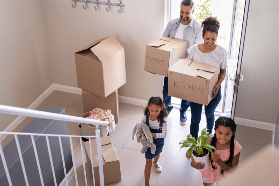 young family walking through the door of their new home with moving boxes 