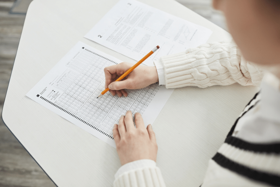 Person taking an exam on a white desk with a pencil