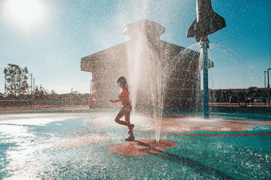 Girl running through a splash pad on a hot day
