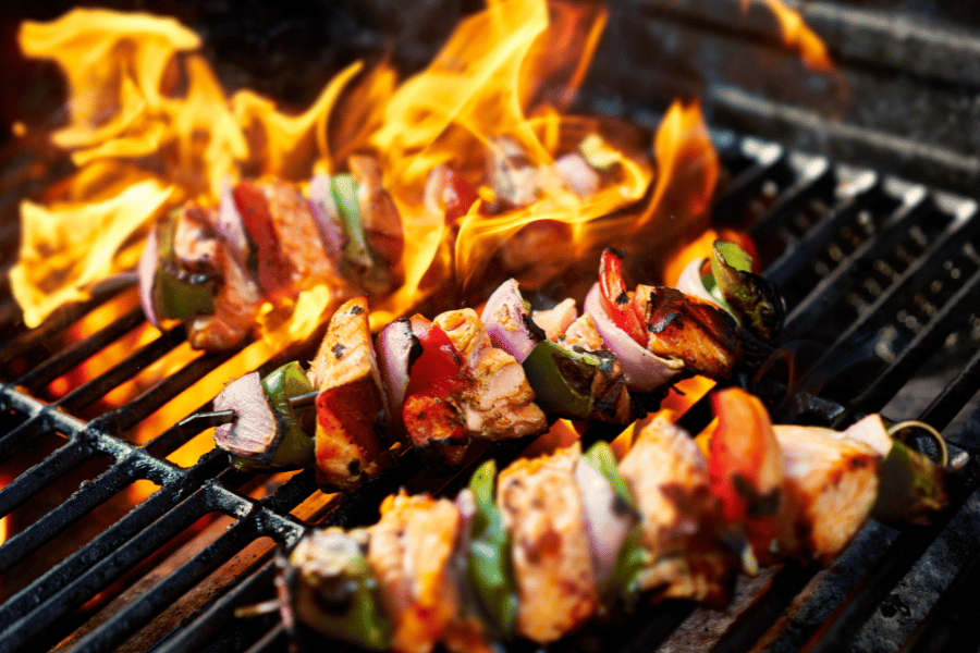 Flaming grill with chicken kabobs with vegetables cooking