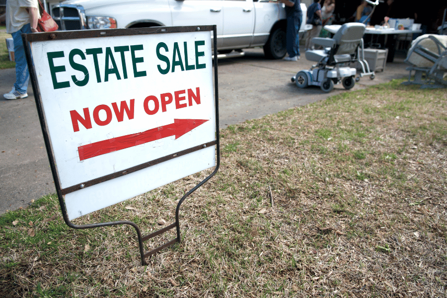 Estate Sale sign in a front yard near plants 