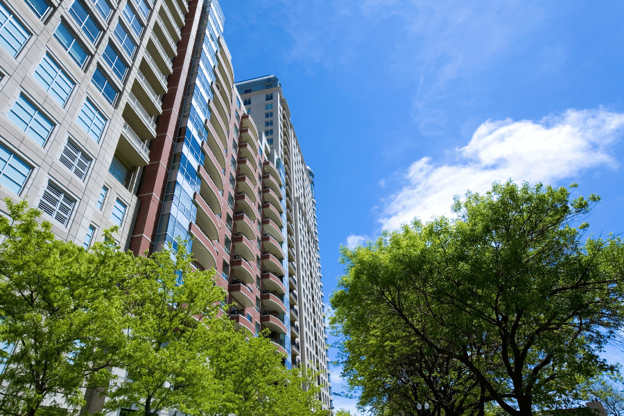 tall luxury condos with balconies surrounded by large trees 