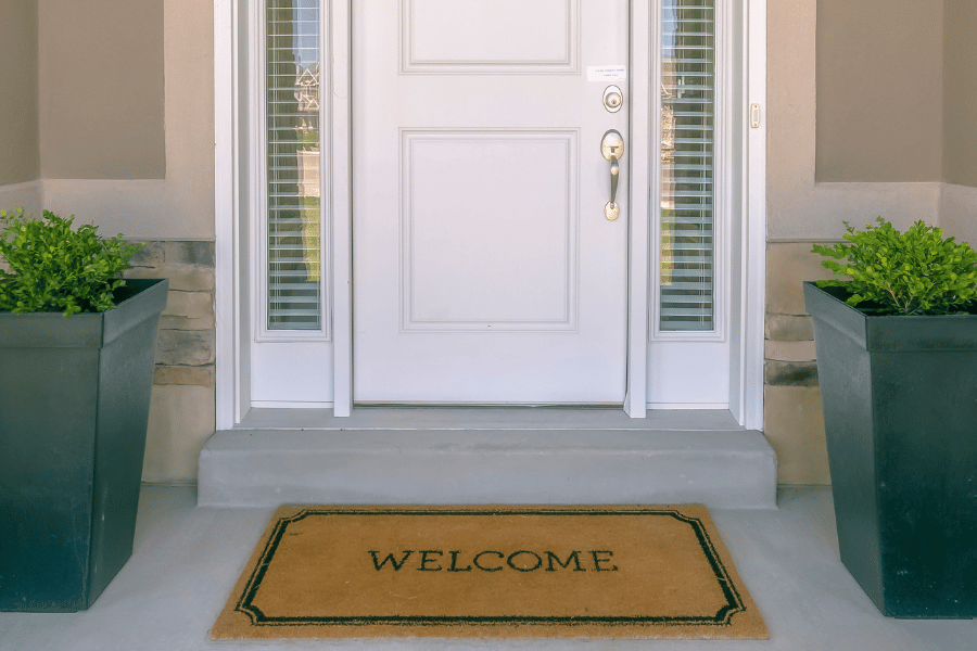 white front door with welcome mat and plants