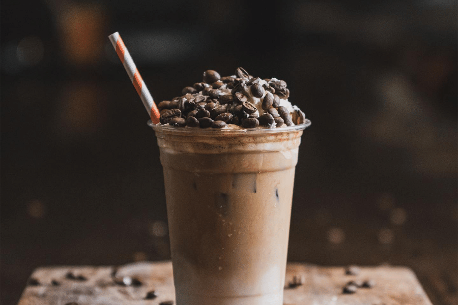 Iced coffee drink with coffee beans and red and white straw 