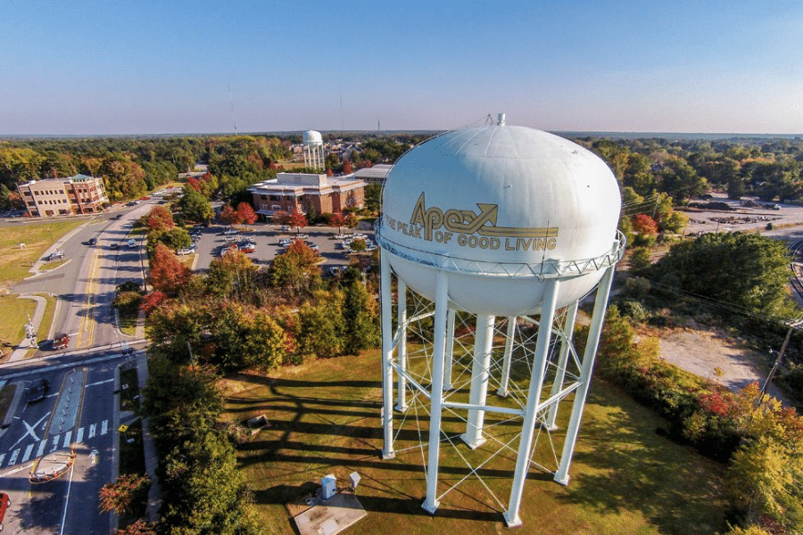 Apex water tower surrounded by beautiful trees, greenery, and the street 