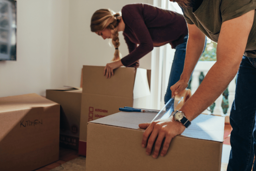 young couple packing items into boxes and taping them shut