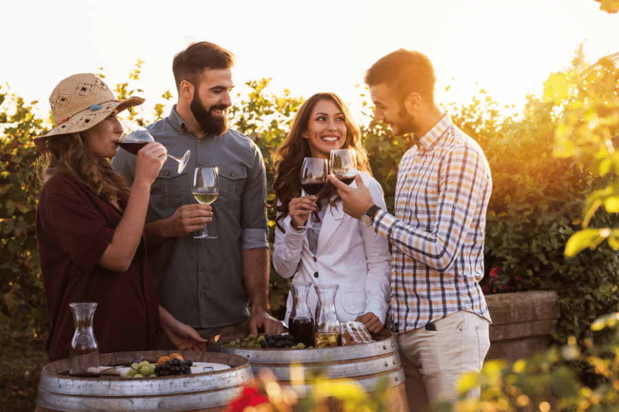 four friends at a winery enjoying good wine together outside