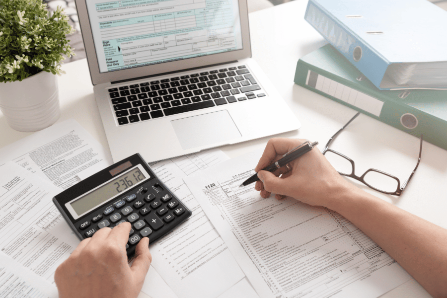 man filing taxes at desk with calculator