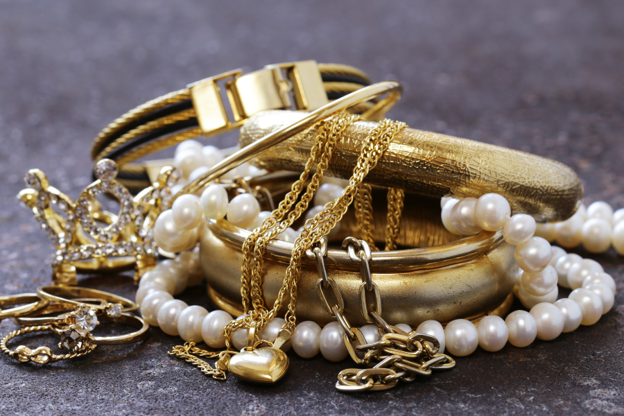 Gold jewelry and heart pendant and pearl necklace in a pile