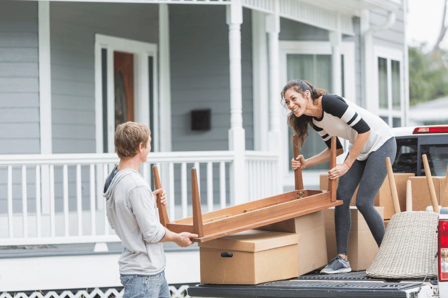 couple moving furniture and boxes into new home