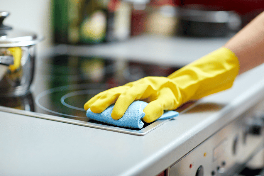property owner cleaning a stove wearing a yellow glove 