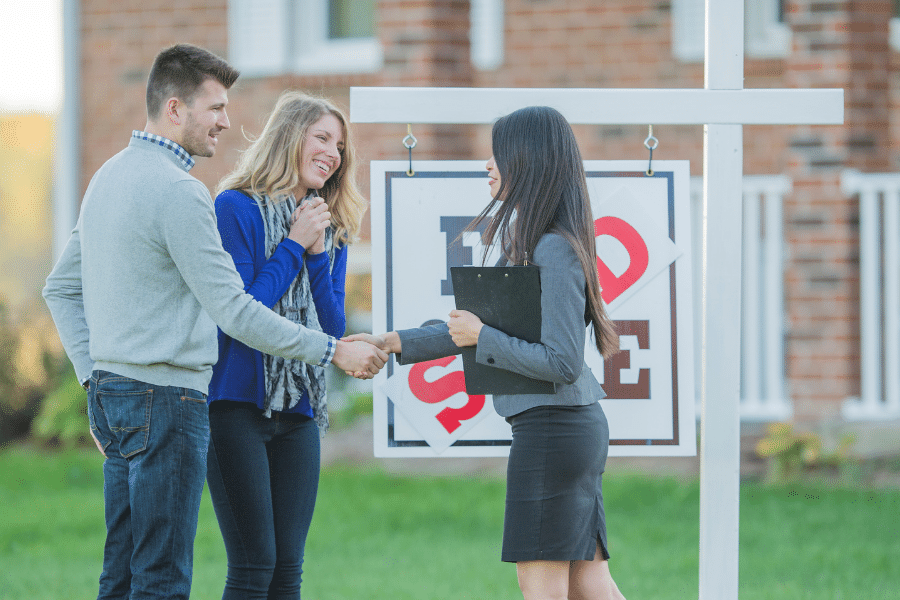 couple buying a home and shaking hands with a realtor