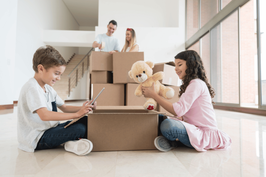 two young kids packing their items into moving boxes with parents