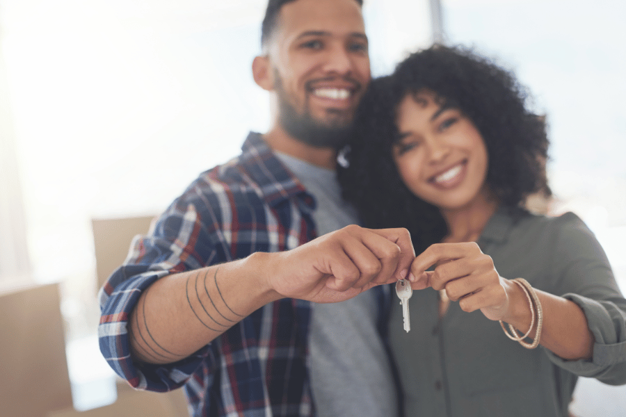 cute couple who are first time homebuyers holding up house key