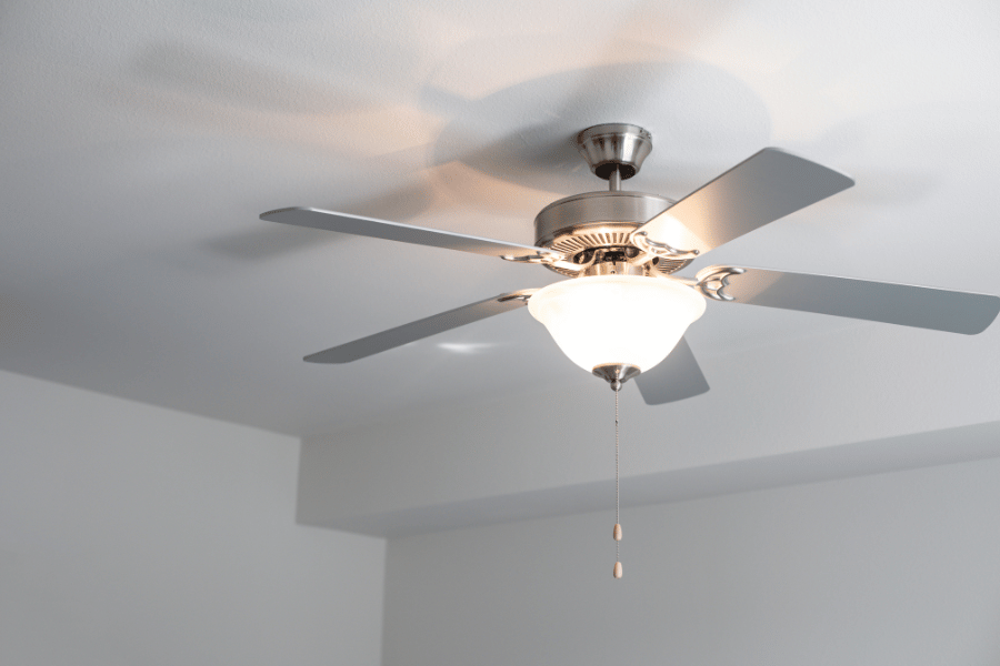 ceiling fan with the light on in a room at home