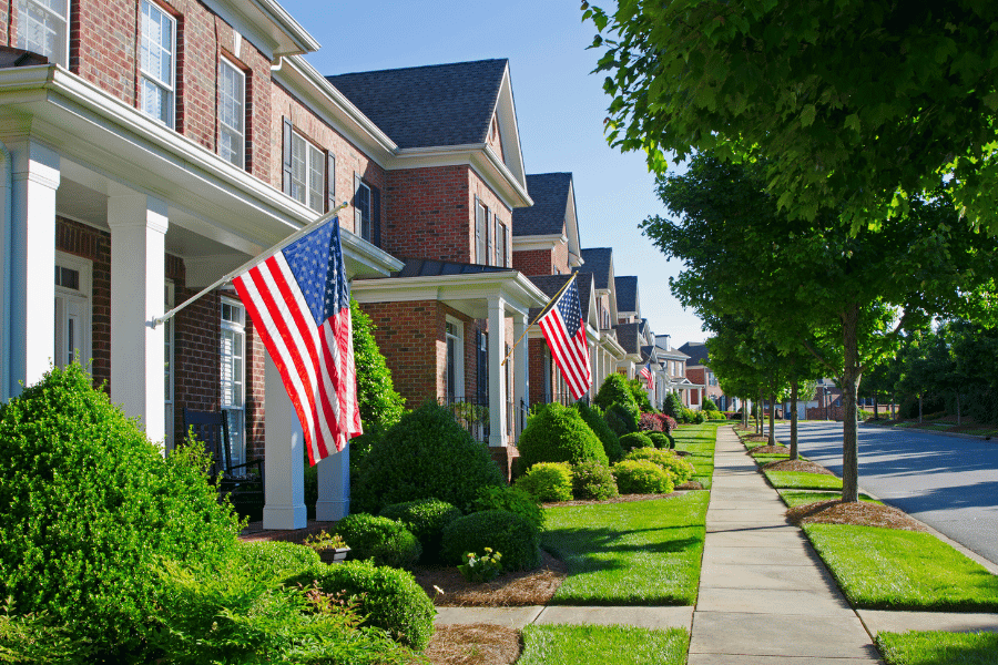 quiet neighborhood with hanging American flags and freshly mowed lawns