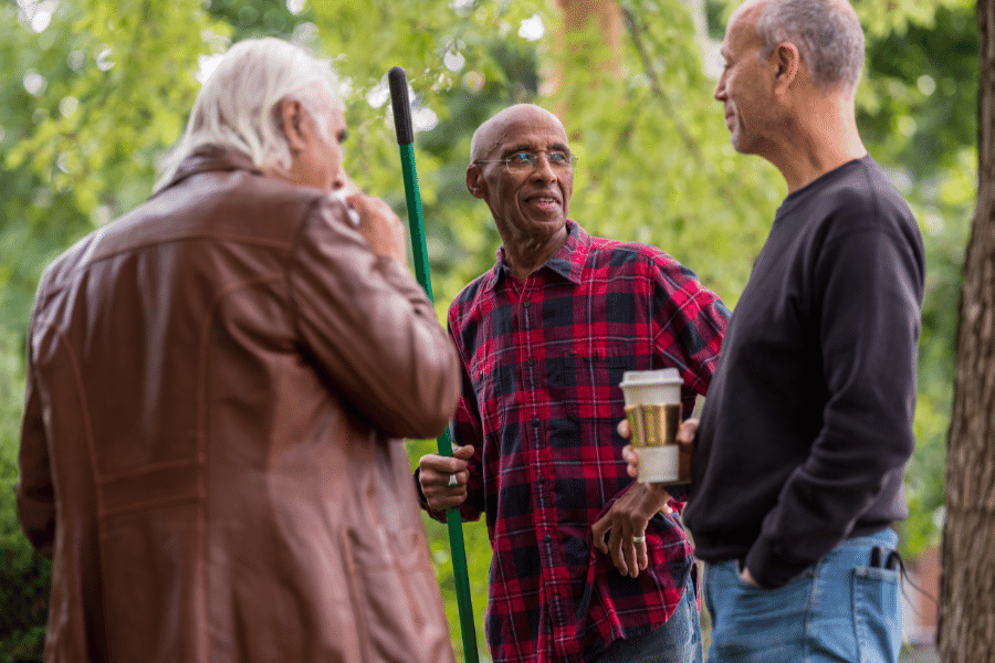 three neighbors outside talking in a yard